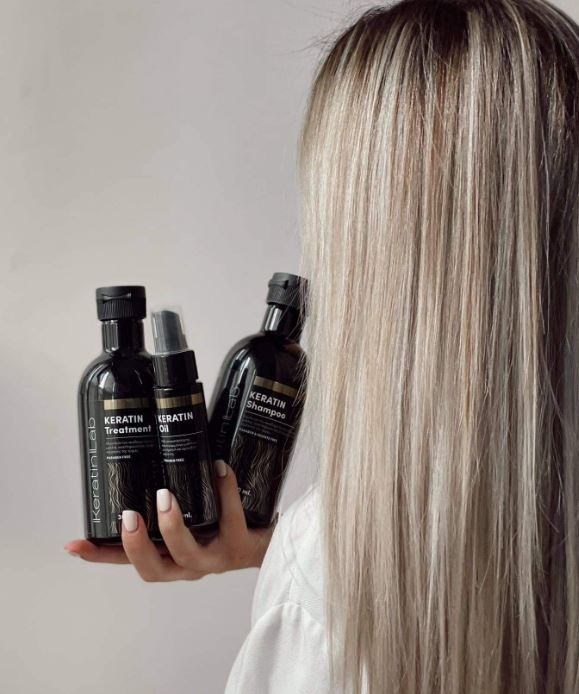 Γυναίκα που κρατά ένα σετ περιποίησης μαλλιών κερατίνης