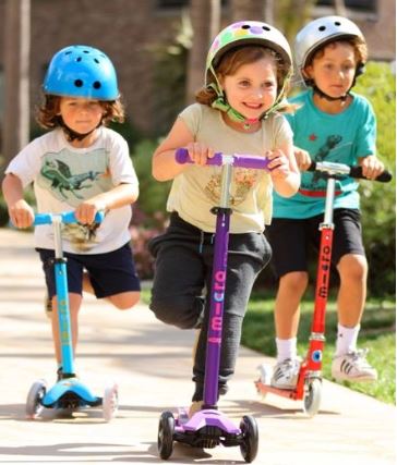 Τα παιδιά οδηγούν πατίνια με ασφάλεια με κράνη