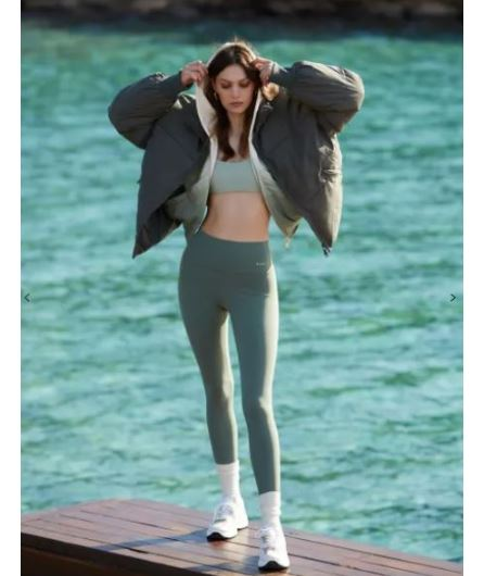 Γυναίκα με χειμερινό μπουφάν, αθλητικά ρούχα δίπλα στη θάλασσα