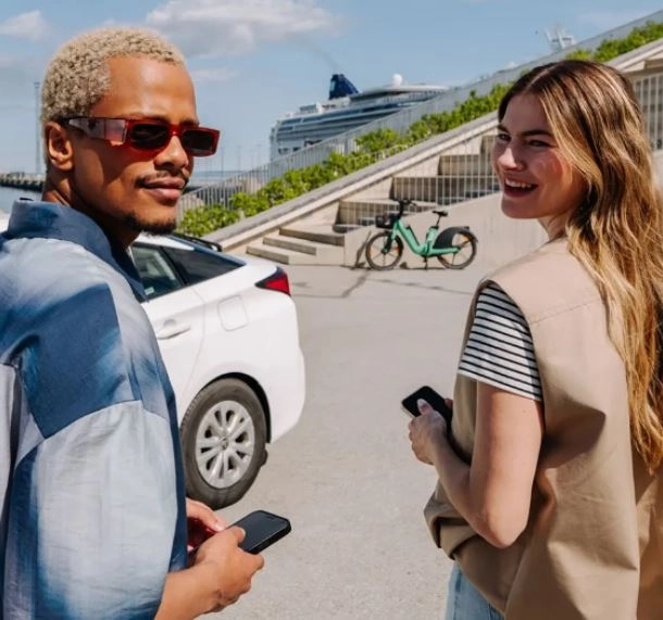 Γυναίκα και άνδρας δίπλα σε λευκό αυτοκίνητο και νοικιασμένο ποδήλατο